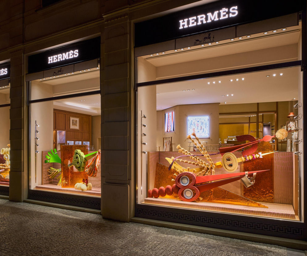 Trzy oświetlone witryny butiku Hermès z artystycznymi instalacjami. O designie w Warszawie i Pradze czytaj w Architektura.