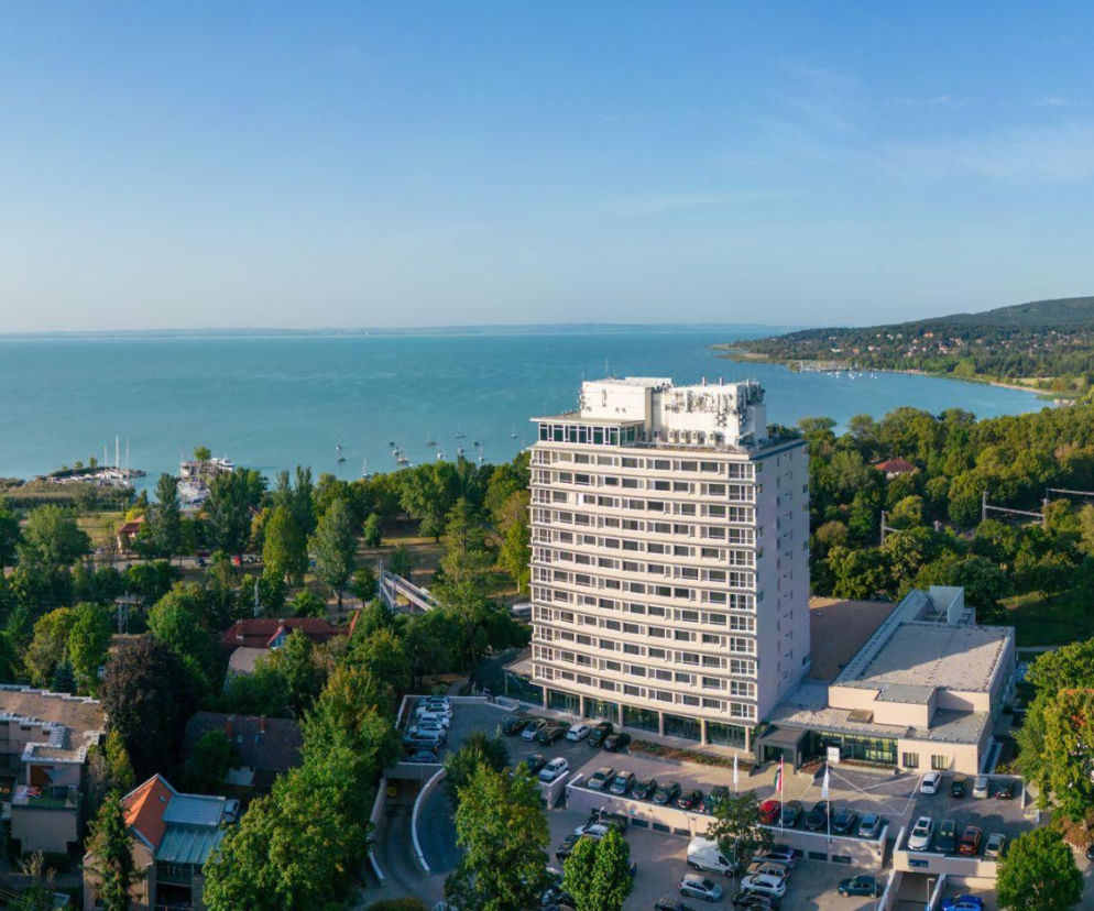 Wielopiętrowy biały hotel Hunguest BÁL Resort otoczony zielenią nad jeziorem Balaton. O atrakcjach dowiesz się z Eska.