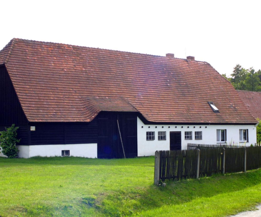 Historyczny dom w Ostaszowie z dachem krytym dachówką. O wpisie wsi do rejestru zabytków przeczytasz na Muratorplus.
