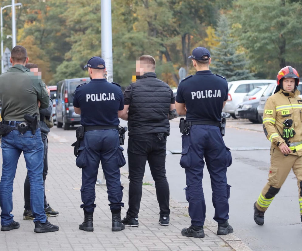 Dwaj policjanci tyłem i strażak na terenie szkoły. O działaniach służb i bezpieczeństwie uczniów przeczytasz na SE.