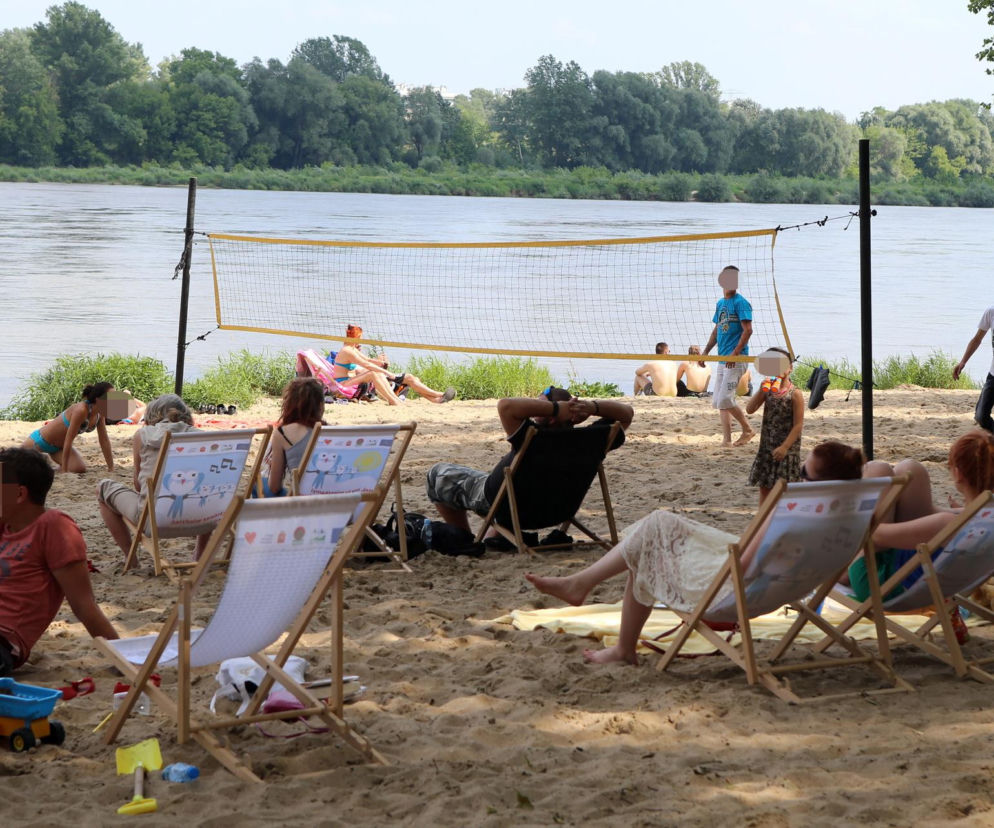 Ludzie odpoczywający na leżakach na piaszczystej plaży nad rzeką. O rozwoju turystyki przeczytasz na SE Superbiz.