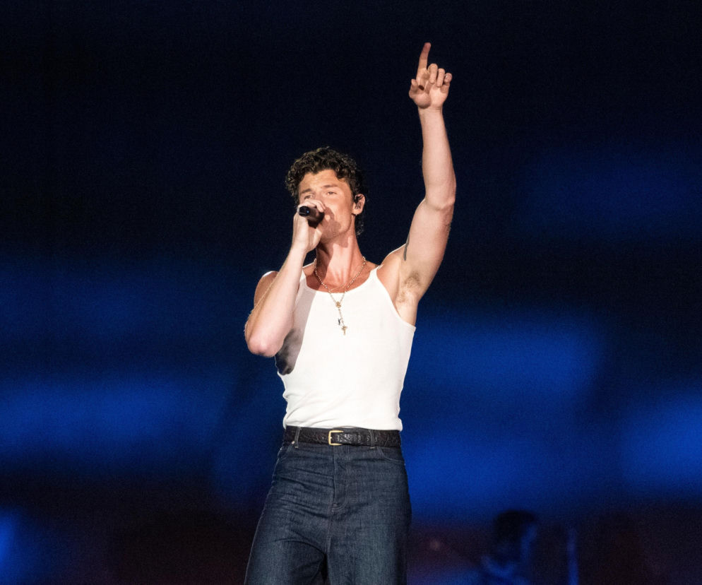 Shawn Mendes śpiewa do mikrofonu na scenie z uniesioną ręką. O jego związku z Bruną Marquezine przeczytasz na Eska.