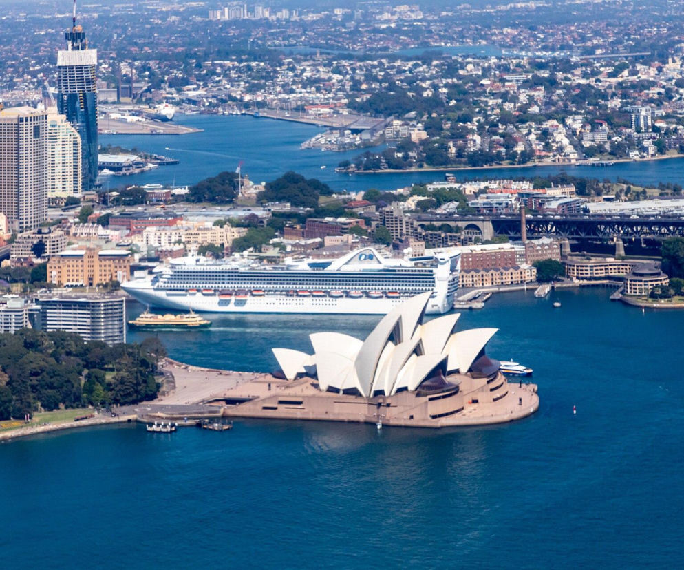 Opera w Sydney z lotu ptaka na tle zatoki i miasta. O historii symbolu Australii przeczytasz w serwisie Architektura.