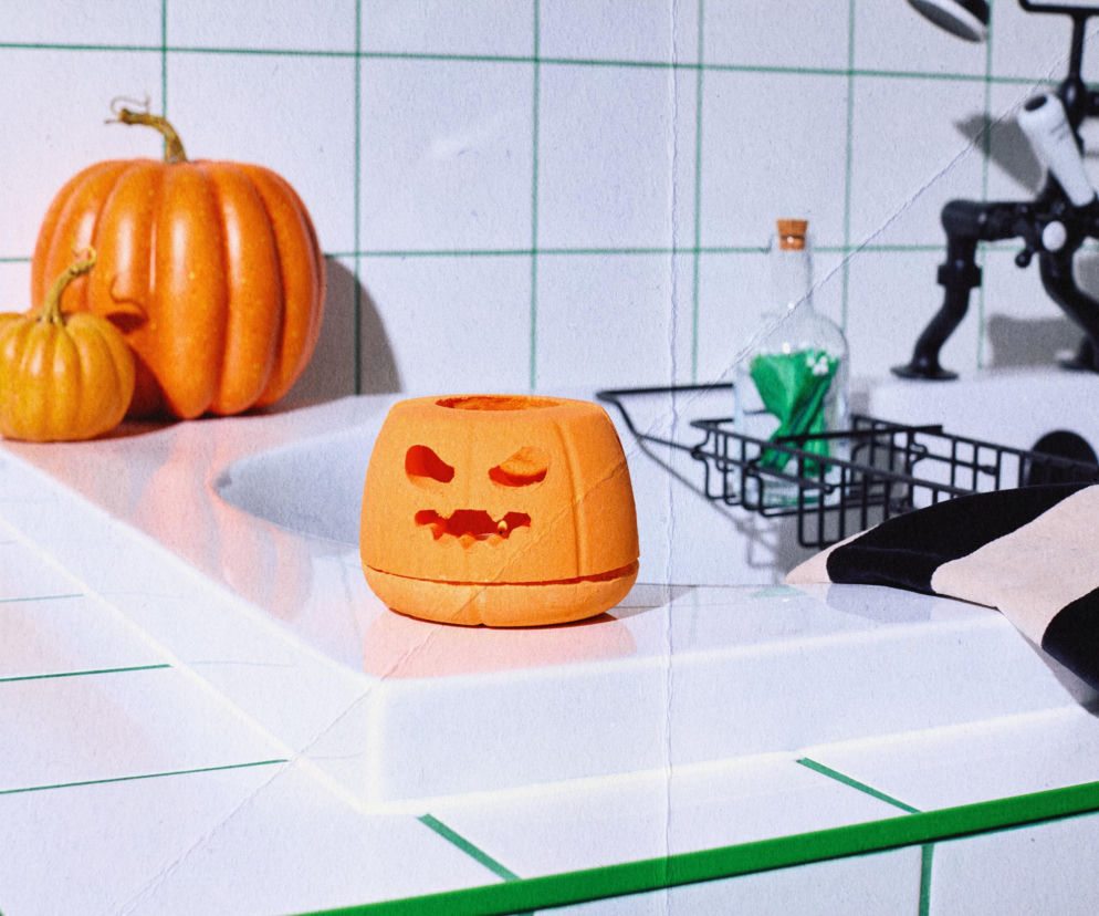 Pomarańczowa kula do kąpieli w kształcie lampionu z dyni na brzegu wanny. O kolekcji Lush na Halloween przeczytasz na SE.