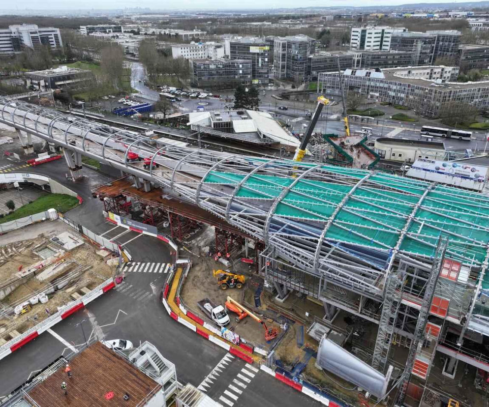 Plac budowy nowoczesnej stacji metra z kładką o szklanej konstrukcji w Paryżu. O inwestycji przeczytasz na Architektura.