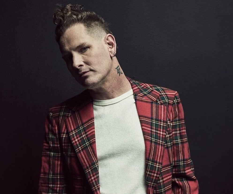 Wokalista Corey Taylor w czerwonej marynarce w kratę na ciemnym tle. O zespole Slipknot przeczytasz na EskaRock.