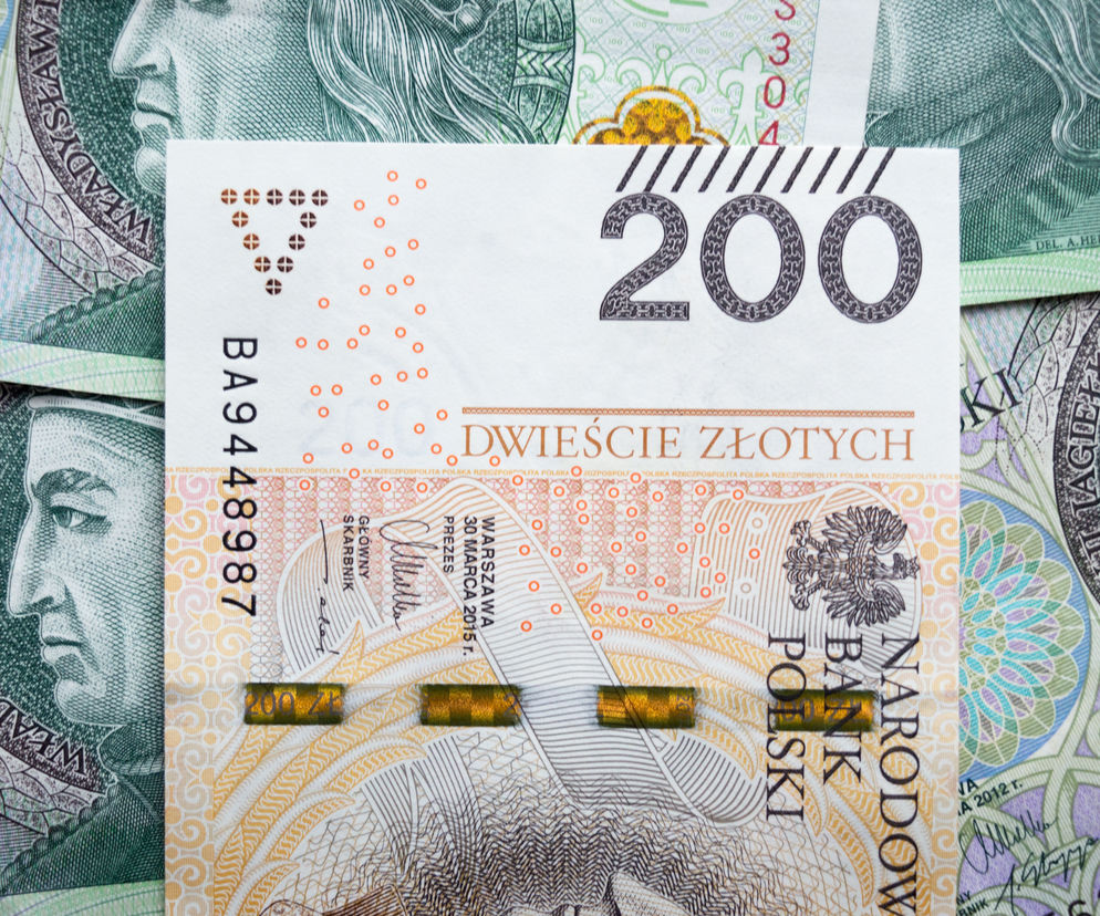 Banknot 200 złotych na tle innych nominałów, co symbolizuje wysokie zarobki w NBP. Temat pensji w Narodowym Banku Polskim, w tym inflacji i danych NBP, znajdziesz na Super Biznes.