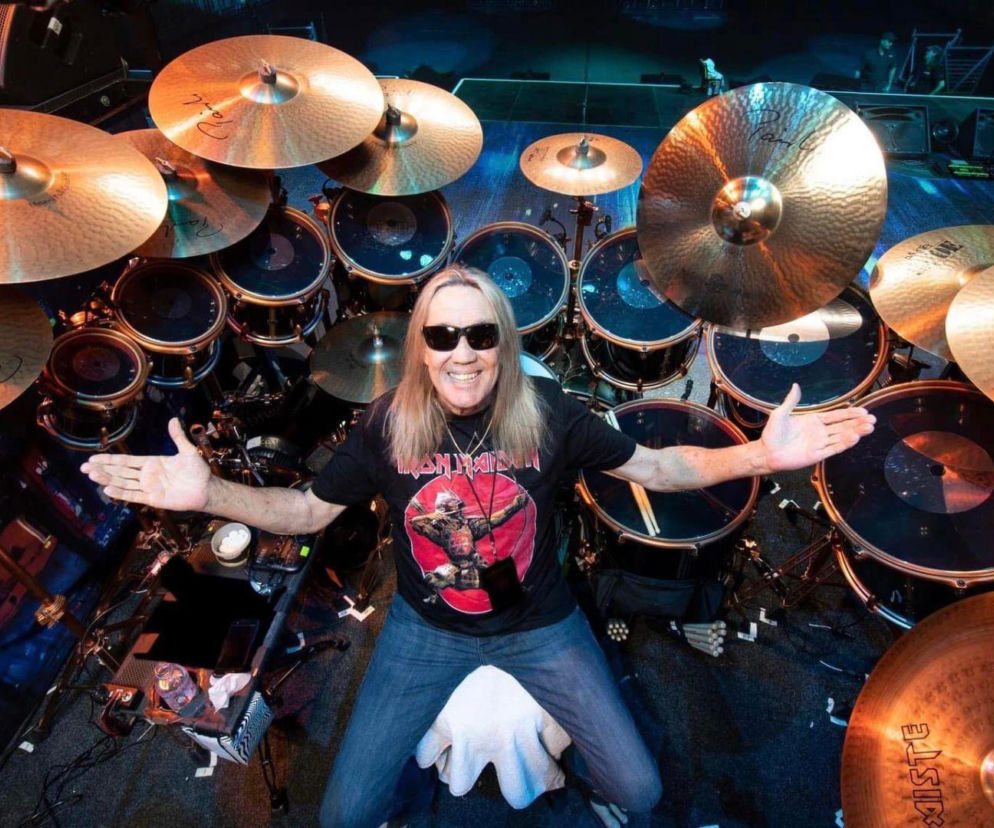 Uśmiechnięty perkusista Nicko McBrain siedzi przy swoim zestawie perkusyjnym. O planach muzyka przeczytasz na EskaRock.