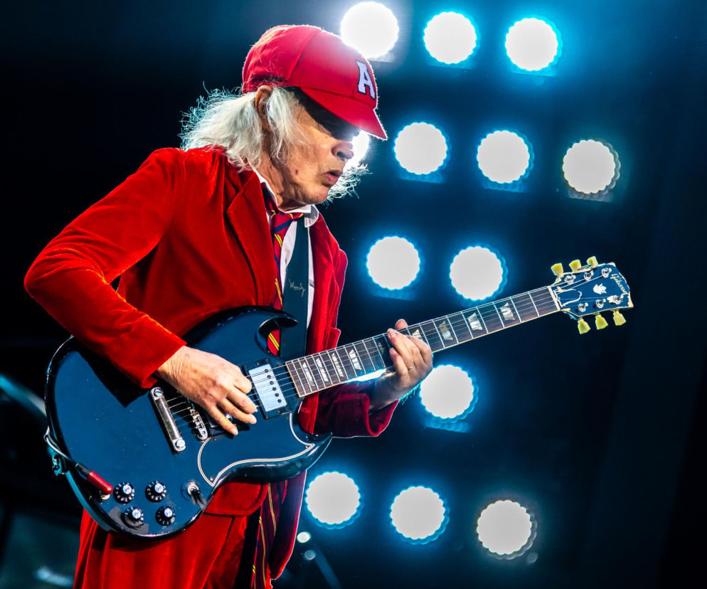 Gitarzysta Angus Young z AC/DC gra na czarnej gitarze. O historii utworu zespołu przeczytasz na EskaRock.