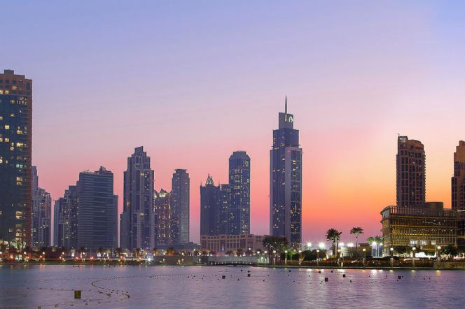 Panorama Dubaju o zachodzie słońca, z podświetlonymi drapaczami chmur i odbiciami w tafli wody. Ta dynamiczna perspektywa ukazuje rozwój infrastruktury ZEA i ich dążenie do uniezależnienia handlowego, o czym przeczytasz na Super Biznes.