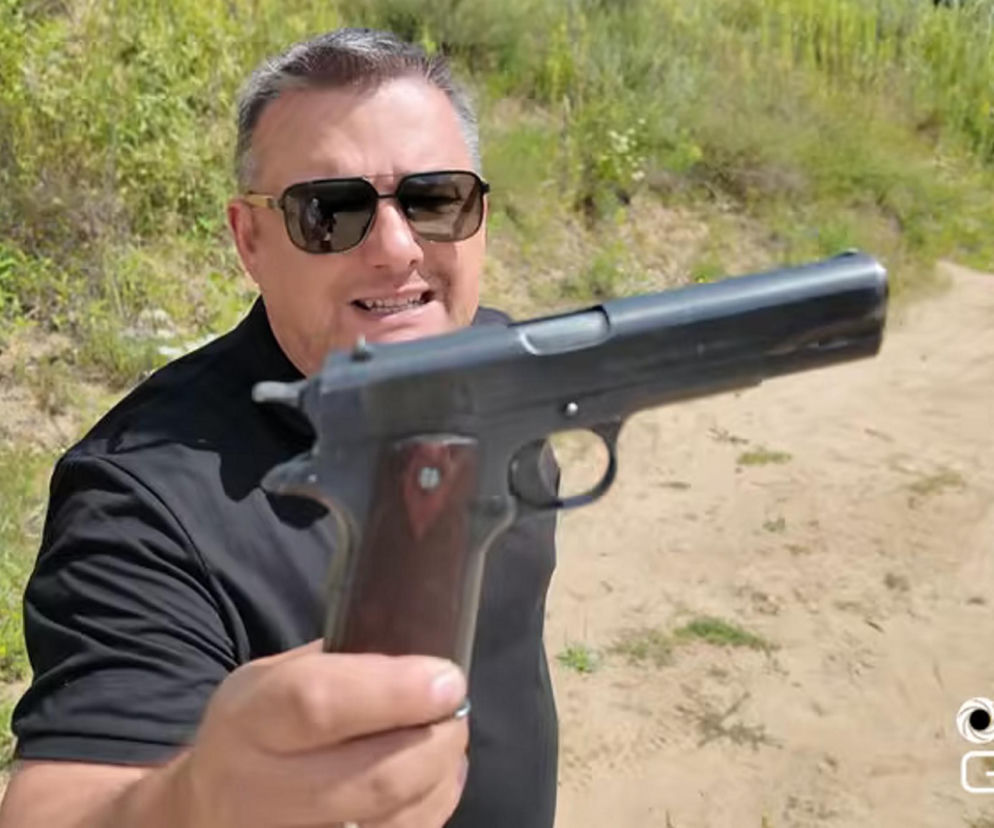 Mężczyzna w ciemnych okularach trzyma pistolet Colt M1911. O ewolucji tej broni przeczytasz na SE Portal Obronny.