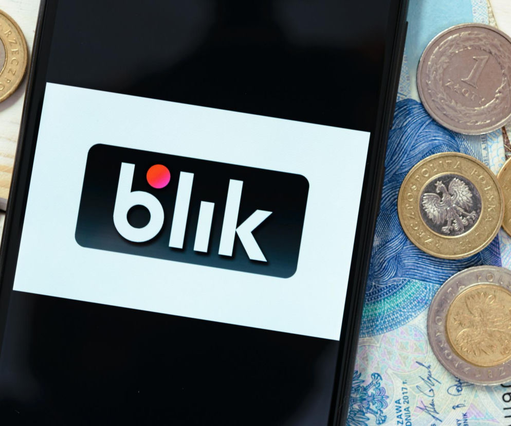 Smartfon z aplikacją BLIK na ekranie, leżący na banknocie 50 złotych i monetach, symbolizujący awarię BLIK-a i PKO BP oraz problemy z płatnościami. Więcej o problemach z BLIK-iem i PKO BP przeczytasz na portalu Super Biznes.
