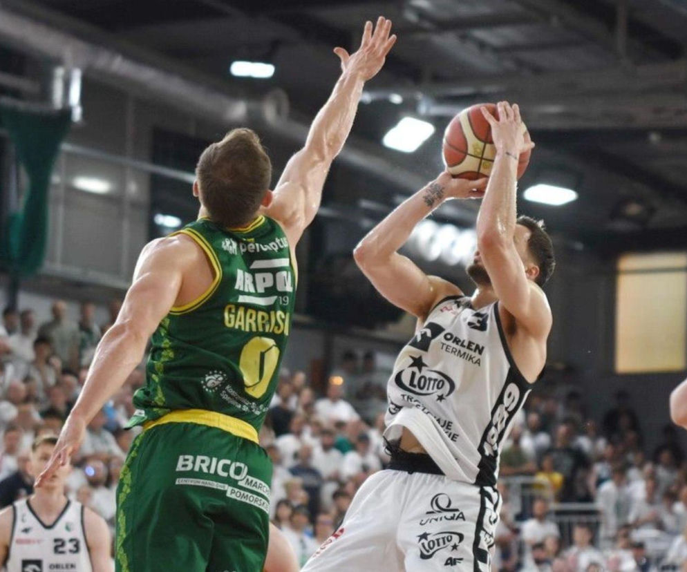 Koszykarz Legii Warszawa, Dominic Brewton III, w białej koszulce z numerem 3, oddaje rzut do kosza, blokowany przez zawodnika Zastalu Zielona Góra, Conley’a Garrisona, w zielonej koszulce z numerem 19, podczas finału Orlen Basket Ligi. O wynikach meczu i mistrzostwie przeczytasz na naszym portalu.