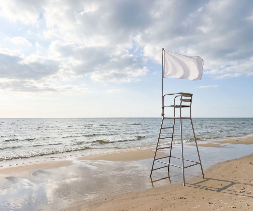 Biała flaga na wieży ratowniczej na pustej plaży w Jastrzębiej Górze. O warunkach kąpieli przeczytasz w Eska Trójmiasto.