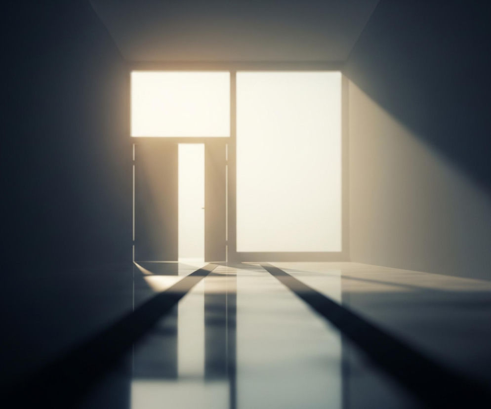 Długi, ciemny korytarz prowadzi do jasno oświetlonego końca, gdzie widać okno i otwarte drzwi, wypełnione białym i żółtawym światłem. Na podłodze widoczne są wyraźne, długie, ciemne cienie, równoległe do ścian, które rozciągają się od frontu obrazu aż do źródła światła, a także jego odbicia na lśniącej powierzchni. Przestrzeń wokół okna i drzwi jest rozświetlona, natomiast reszta korytarza pozostaje w głębokim cieniu, tworząc kontrast między ciemnością a jasnością.