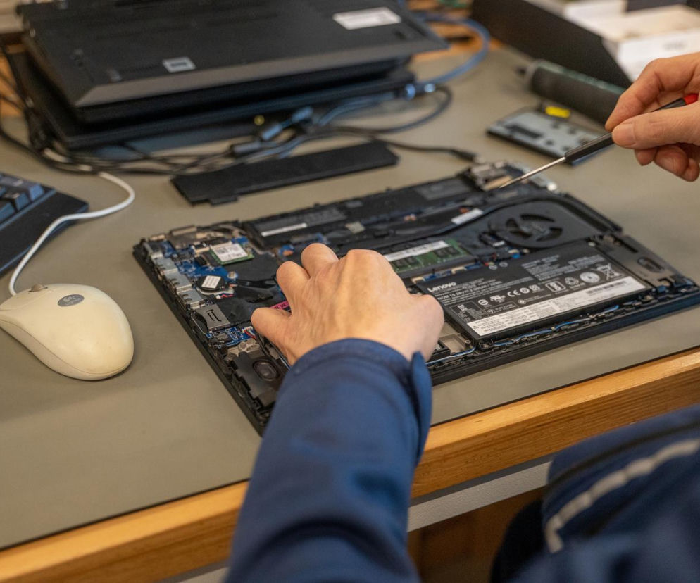 Dłonie osoby naprawiającej wnętrze laptopa śrubokrętem. O ustawie Right to Repair przeczytasz na SE Superbiz.