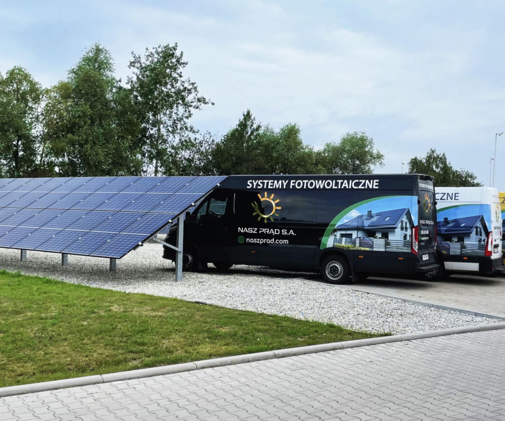 Flota furgonetek firmy Nasz Prąd S.A. obok farmy fotowoltaicznej. O sukcesie wrocławskiej spółki przeczytasz na SE.
