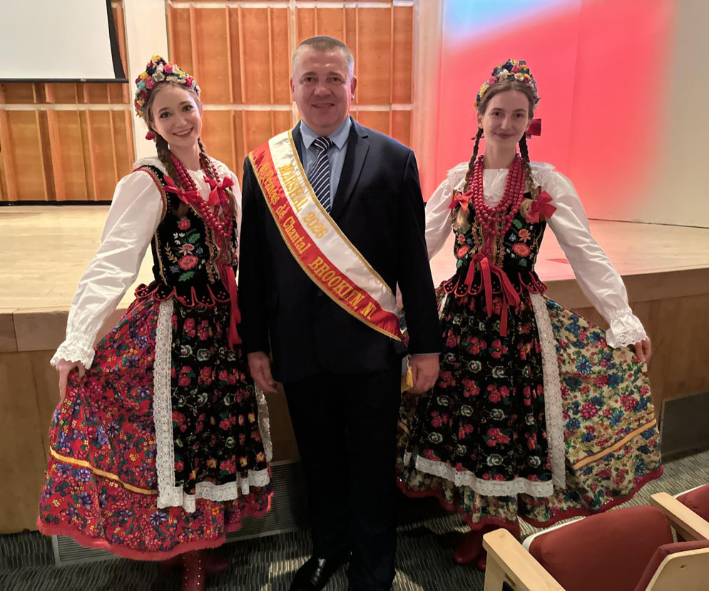 Marszałek Paweł Poliwka w szarfie z dwiema kobietami w ludowych strojach. O Paradzie Pułaskiego przeczytasz na SE USA.