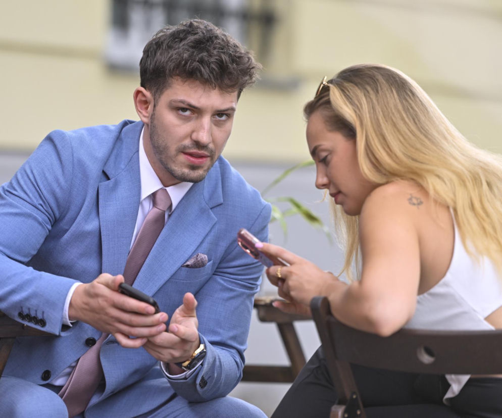 Aktor Jasper Sołtysiewicz w niebieskim garniturze i Wiktoria Gąsiewska patrzą w telefony. O parze przeczytasz w VOX FM.