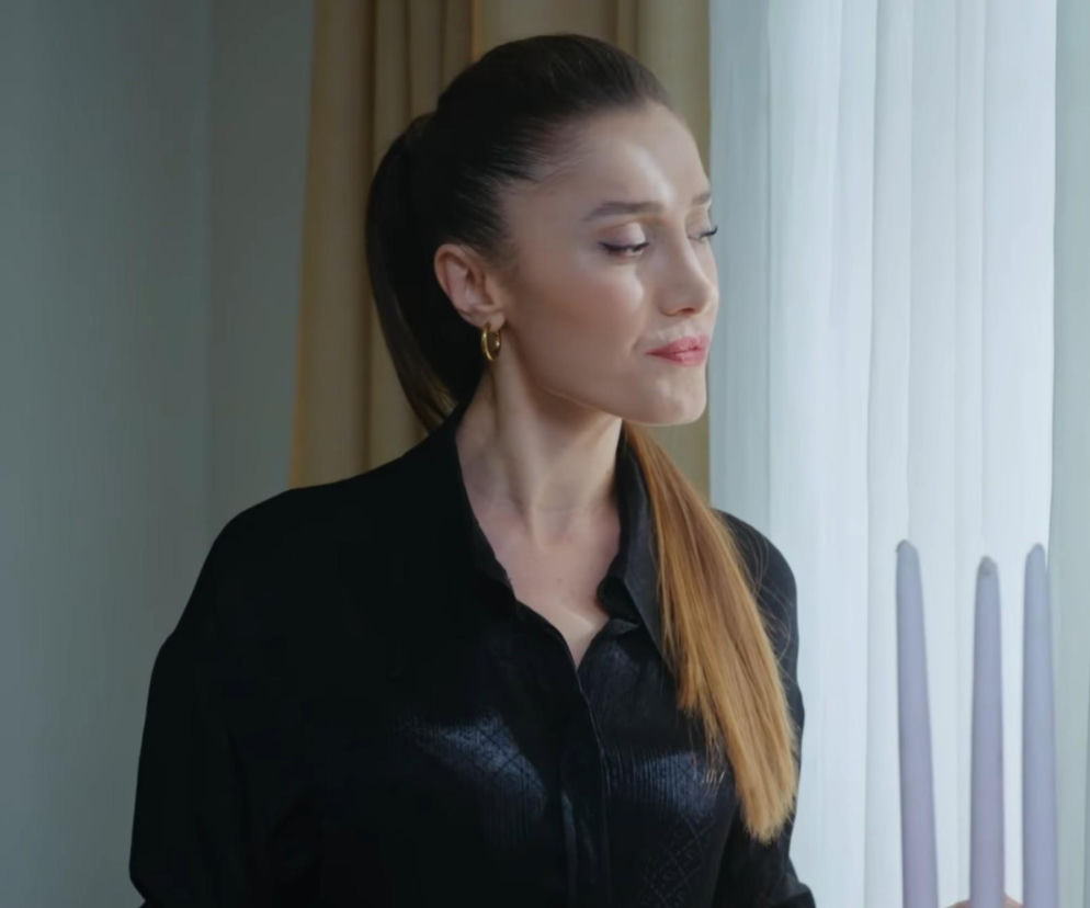 Derya, bohaterka serialu Dziedzictwo, patrzy w bok, a jej wyraz twarzy sugeruje zamyślenie lub niepokój. Ubrana w czarną koszulę, z włosami spiętymi w kucyk, kobieta wydaje się planować ucieczkę przed policją w 944. odcinku. Więcej informacji o serialu znajdziesz na Super Seriale.