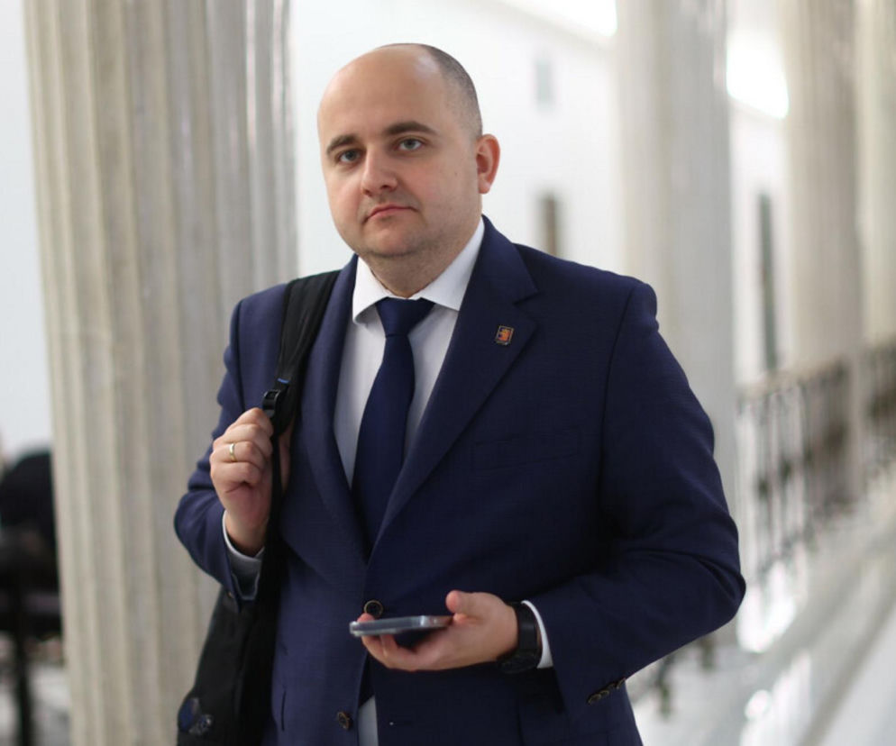 Poseł Dariusz Matecki w garniturze stoi w korytarzu sejmowym. O jego interpelacji w sprawie symboli na granicy przeczytasz na SE Polityka.