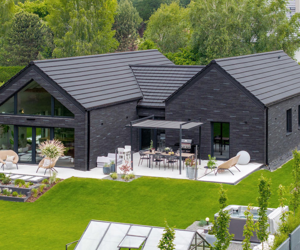 Nowoczesny dom w stylu stodoły z dachem z ciemnej dachówki ceramicznej. O projektach modern barn przeczytasz na Muratordom.