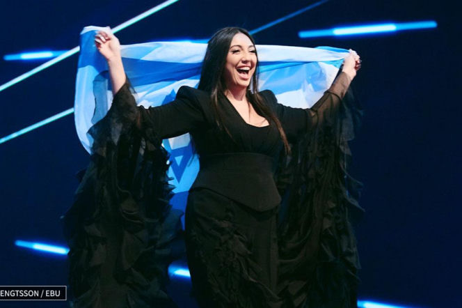 Uśmiechnięta piosenkarka z flagą Izraela na scenie Eurowizji. O nowych zasadach konkursu przeczytasz na SE.