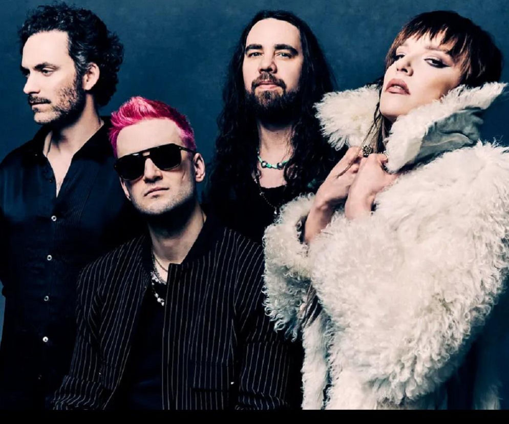 Zespół Halestorm na ciemnym tle. Wokół wokalistki w białym futrze stoją muzycy. O Pol’and’Rock 2027 przeczytasz w EskaRock.