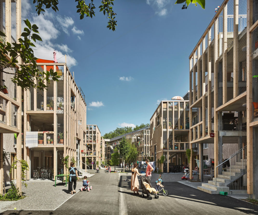 Mieszkańcy osiedla Huebergass w Bernie na spacerze między budynkami. O nowym modelu budownictwa przeczytasz na Architektura.