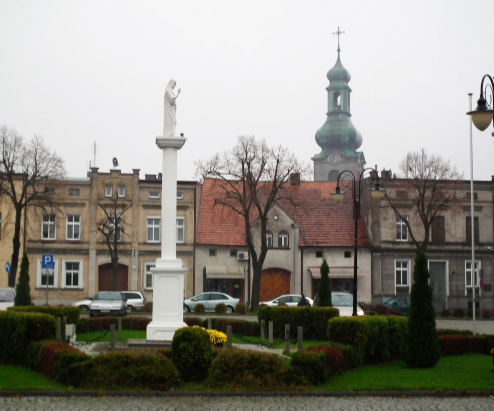 Rynek w Mikstacie z pomnikiem i wieżą kościoła. O demografii miasta przeczytasz na Eska Poznań.