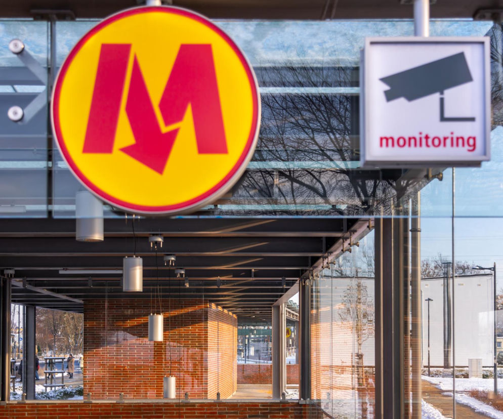 Wejście do stacji metra z logotypem M i tabliczką monitoringu. O budowie PKP Warszawa Ulrychów pisze Architektura.