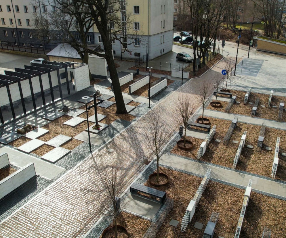 Widok z góry na węzeł przesiadkowy Olsztyn-Śródmieście i upamiętnienie dawnego cmentarza ewangelickiego. Park miejski z pawilonem pamięci, ścianami kurtynowymi z nazwiskami, lapidarium oraz gabionami. Więcej o Architektura Murator Plus.