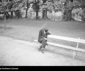Starszy mężczyzna siedzący na ławce w alei parkowej. 1936 rok