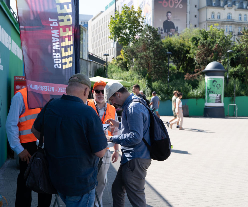 Mężczyzna podpisujący petycję przy stoliku na ulicy Warszawy. O referendum w stolicy przeczytasz na Eska Warszawa.