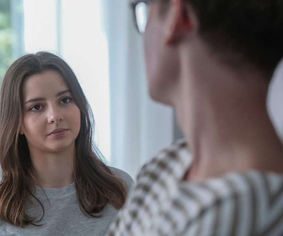 Ewa (Gabriela Ziembicka) z poważną miną rozmawia z Aleksem (Hubert Wiatrowski), którego widać od tyłu. Napięcie między bohaterami w serialu Barwy szczęścia jest wyczuwalne. O szczegółach ich relacji przeczytasz na portalu Super Seriale.