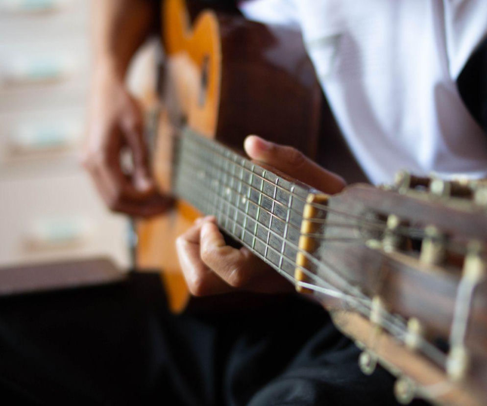 Dłonie osoby grającej na gitarze klasycznej. O tym, jakie utwory Polacy najchętniej grają, przeczytasz na Eska.