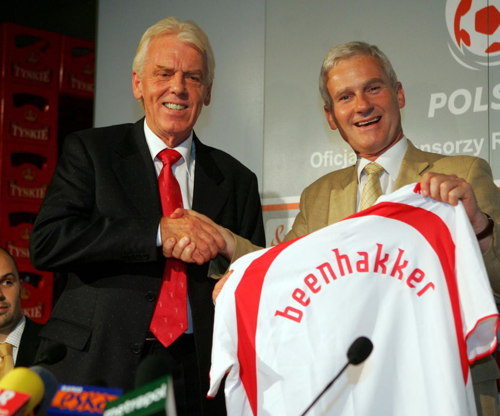 Uśmiechnięty Leo Beenhakker podaje rękę Michałowi Listkiewiczowi trzymającemu koszulkę kadry. Historię trenera poznasz na SE.