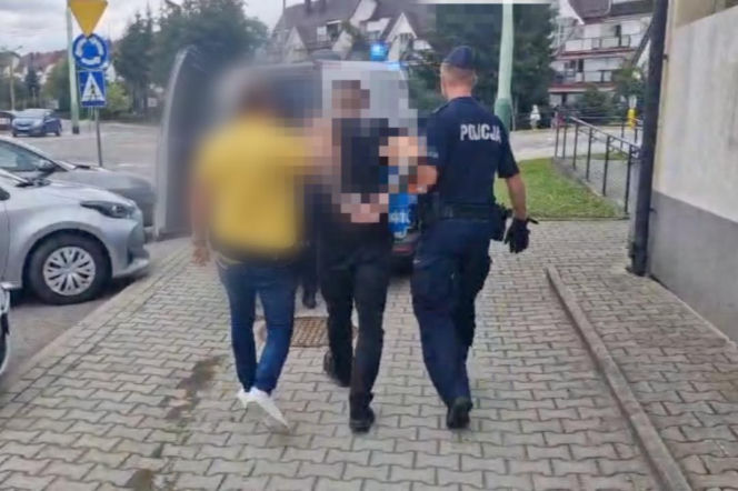 Policjant prowadzi dwóch zatrzymanych mężczyzn do radiowozu. O ataku w Dębicy przeczytasz na Eska Rzeszów.