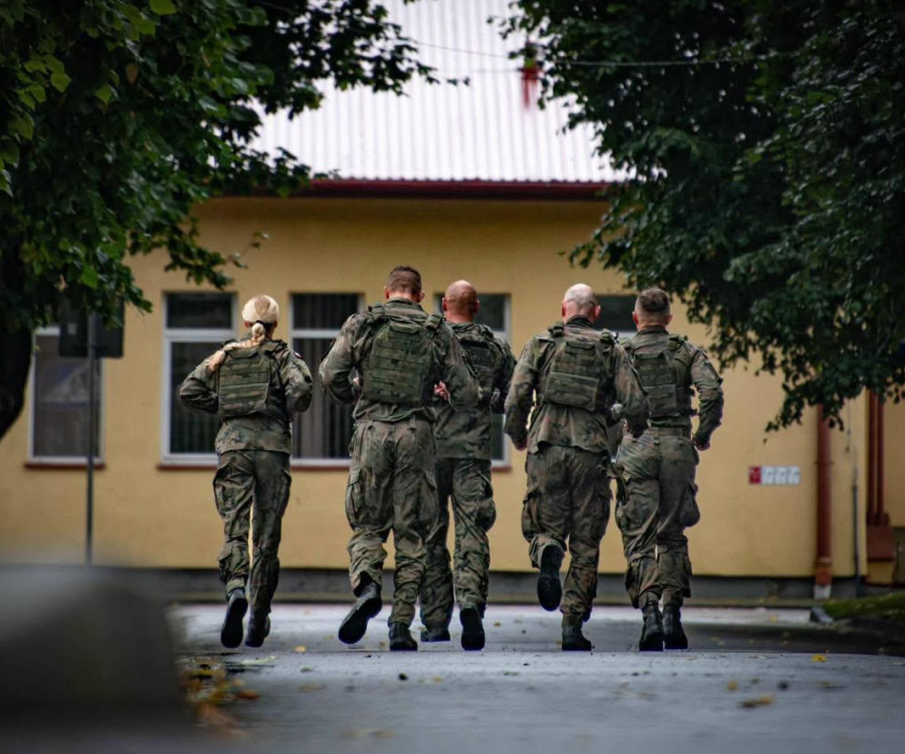Pięciu żołnierzy w pełnym umundurowaniu biegnie w stronę budynku. O ćwiczeniach rezerwy przeczytasz na SE Portal Obronny.
