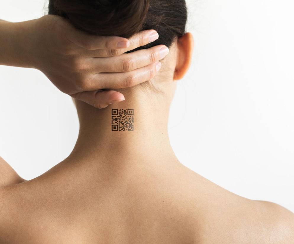 Osoba z odwróconymi plecami i kodem QR na karku, symbolizująca przyszłość monitorowania zdrowia za pomocą wszczepianych technologii. Artykuł na Poradnik Zdrowie omawia postawy Polaków wobec cyborgizacji i medycznych modyfikacji ciała.