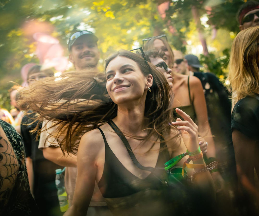 Uśmiechnięta kobieta tańcząca wśród tłumu na festiwalu muzycznym. O Audioriver 2026 w Łodzi przeczytasz w Eska.