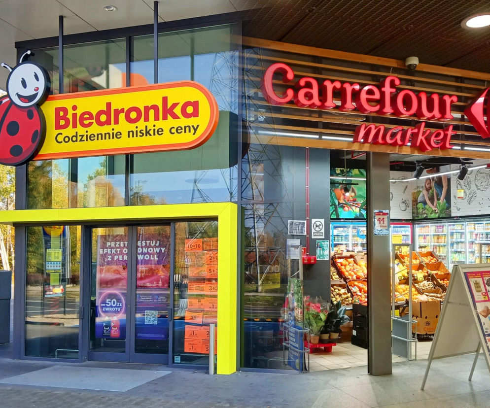 Fronty sklepów Biedronka z charakterystycznym logo biedronki oraz Carrefour Market z czerwonym napisem i symbolem, stojące obok siebie. Wizja potencjalnego przejęcia Carrefoura przez Biedronkę, o czym przeczytasz więcej na Super Biznes.