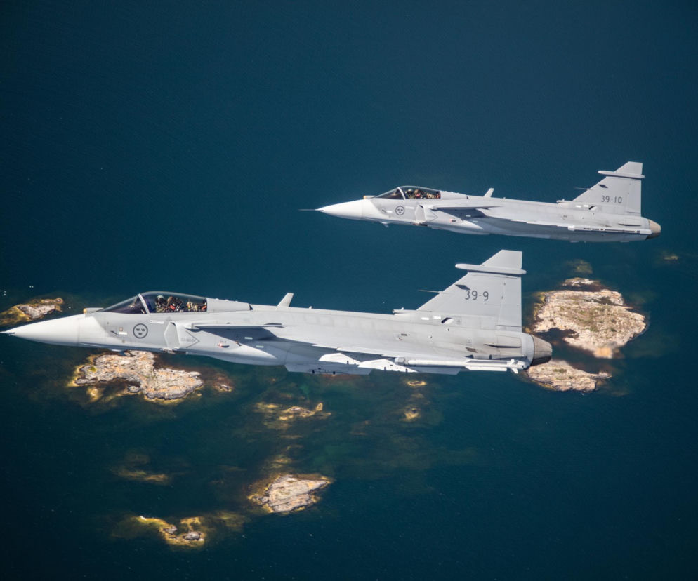 Dwa szwedzkie samoloty Gripen lecą nad wodą. O wsparciu polskiego nieba przez Szwecję przeczytasz na SE Portal Obronny.