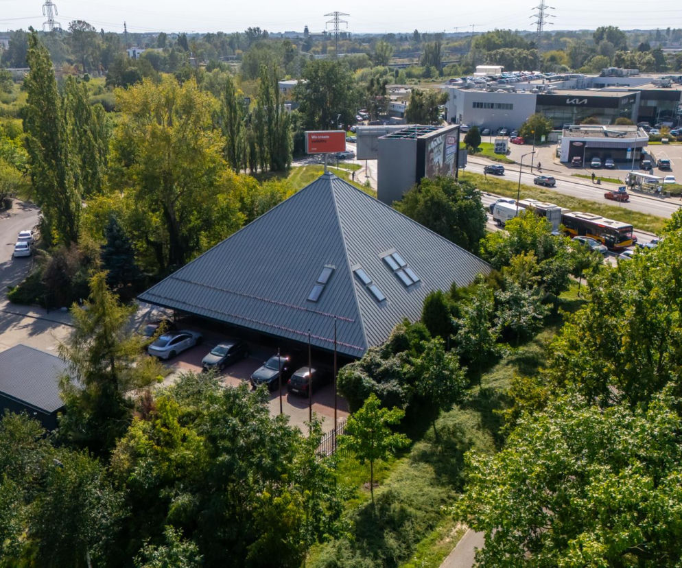 Budynek w kształcie piramidy przy ulicy Połczyńskiej w Warszawie wśród drzew. O jego historii czytaj na Architektura.