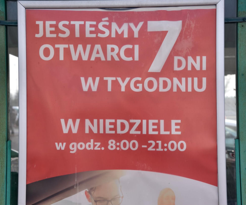 Duży Ben. Duża czerwona plansza z napisem Jesteśmy otwarci 7 dni w tygodniu. W niedzielę w godz. 8:00 - 21:00, informującym o zmianach w funkcjonowaniu sklepów i możliwości robienia zakupów w niedziele, o czym możesz przeczytać na Super Biznes.