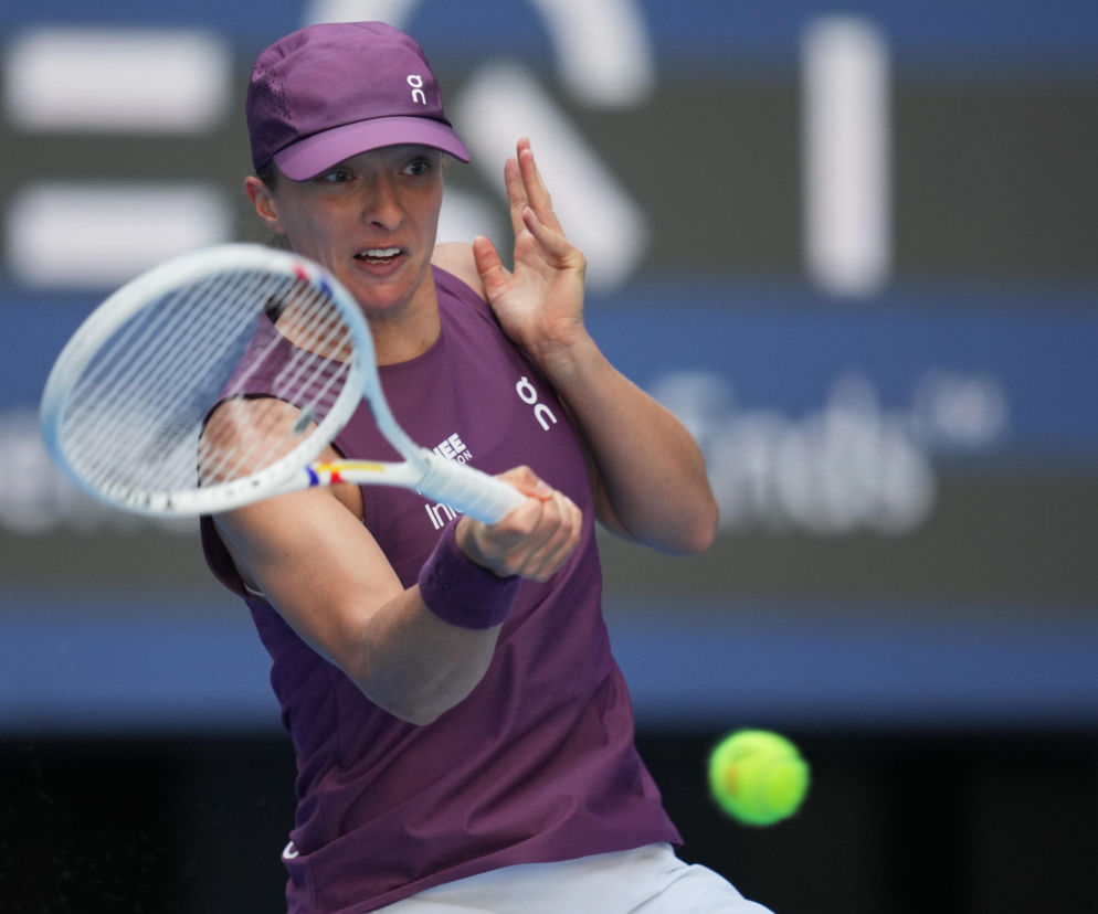 Iga Świątek w fioletowym stroju uderza rakietą w piłkę tenisową. O meczu z Elise Mertens przeczytasz na SE Supersport.