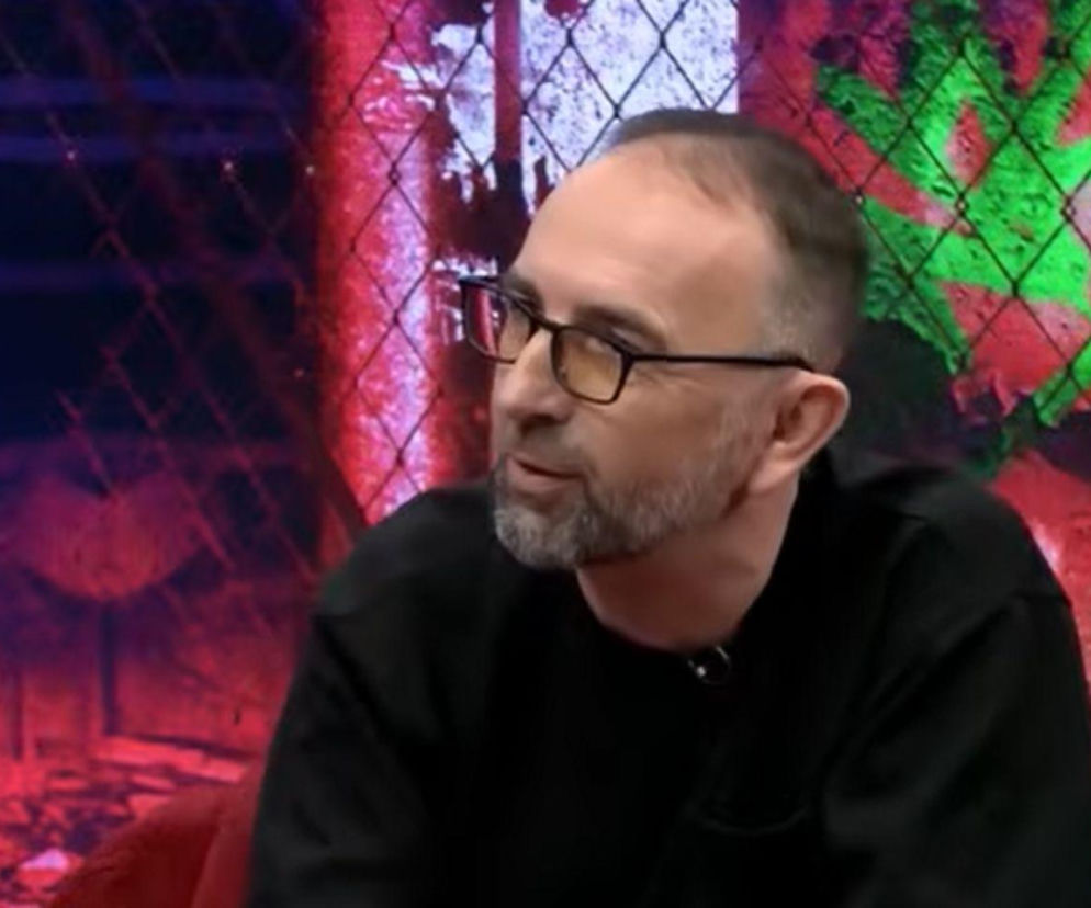 Alek Korab w okularach podczas rozmowy w studio. O realiach życia w USA przeczytasz na Mediateka.