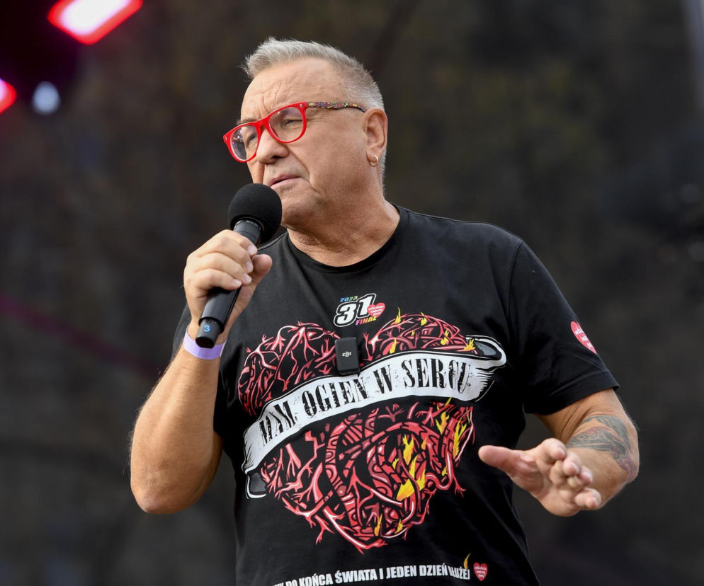 Jerzy Owsiak w czerwonych okularach przemawia do mikrofonu. O ewolucji jego wizerunku przeczytasz na EskaRock.