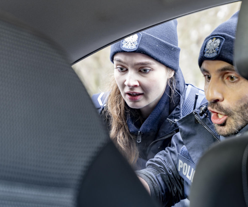 Funkcjonariusze Marek Korwicki i Daria Włodarczyk z serialu Policjantki i Policjanci pochylają się nad czymś w samochodzie, patrząc z zaskoczeniem. Obraz oddaje napięcie i emocje związane z ich nową misją. Więcej o ich losach na Super Seriale.