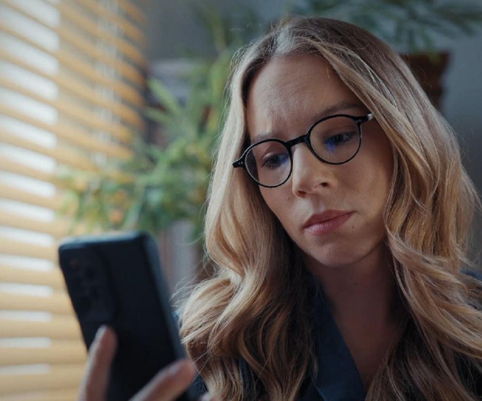 Hanna Turnau w okularach patrzy z przejęciem w telefon. O jej odejściu z serialu M jak miłość przeczytasz na Eska.